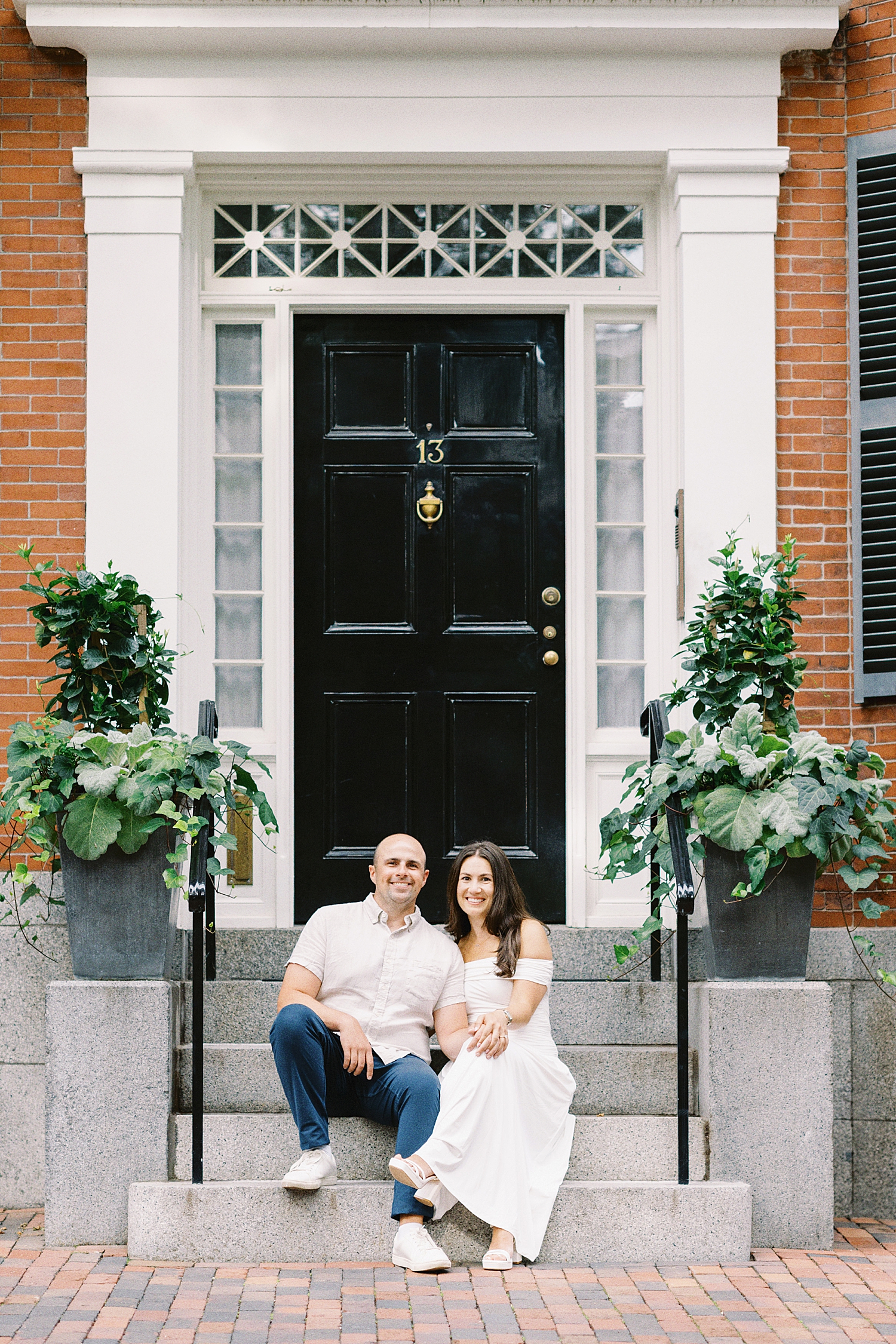 brunette woman sits next to man on steps for Charles River Esplanade Engagement Session