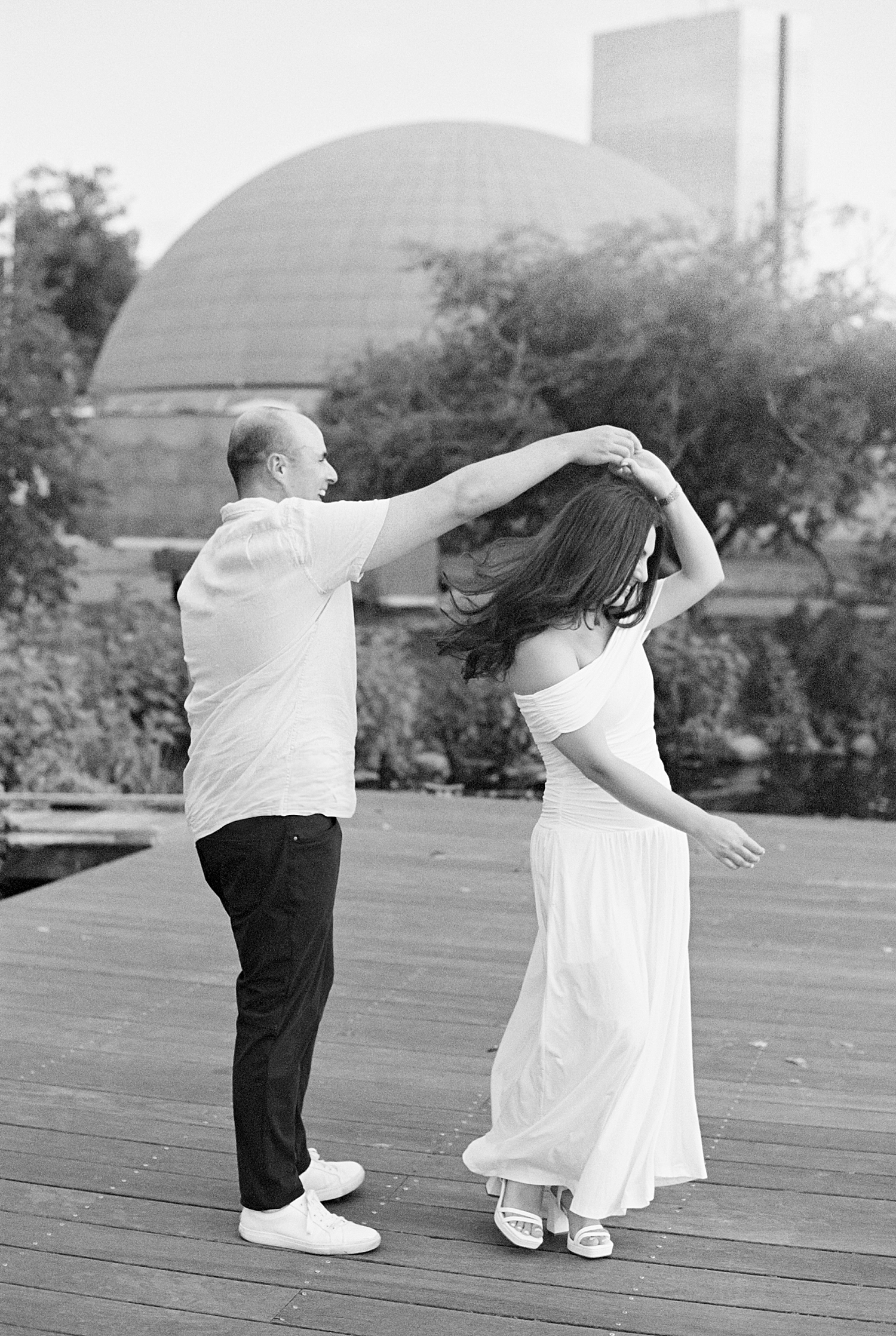 man spins his woman on dock for Charles River Esplanade Engagement Session