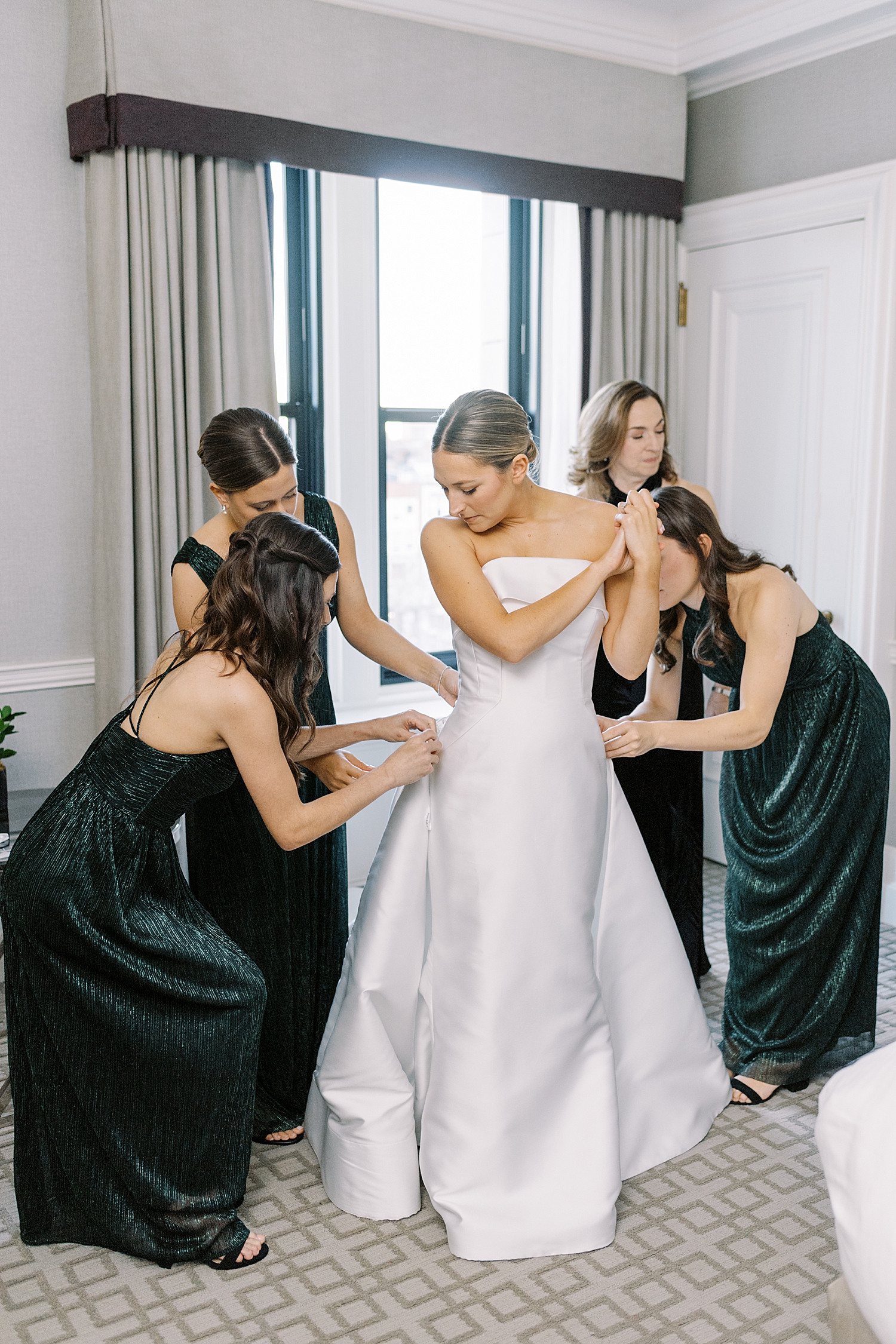 bridesmaids adjust bridal gown in hotel room for NYE wedding weekend