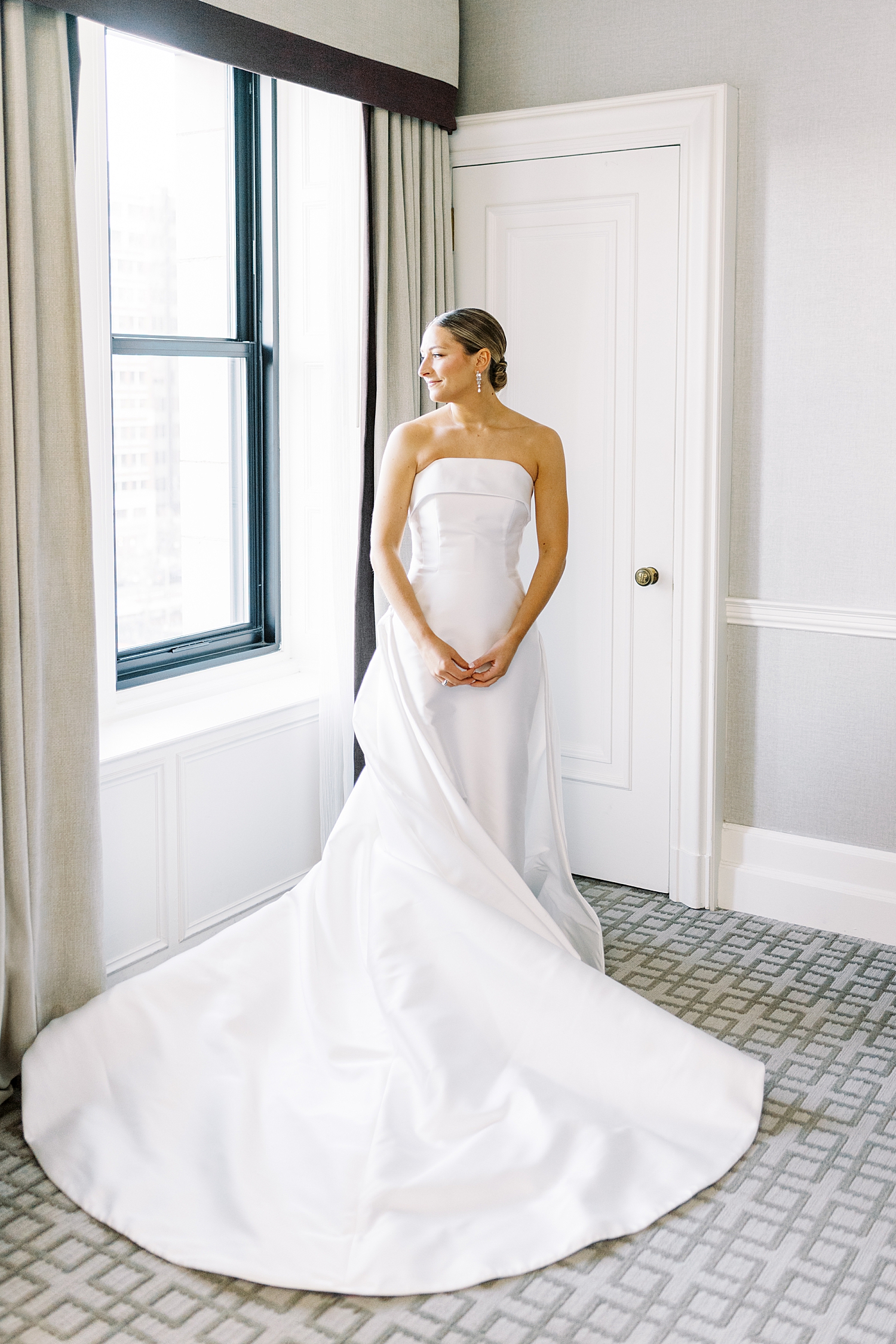 woman in long white bridal gown in front of hotel window by Boston photographer