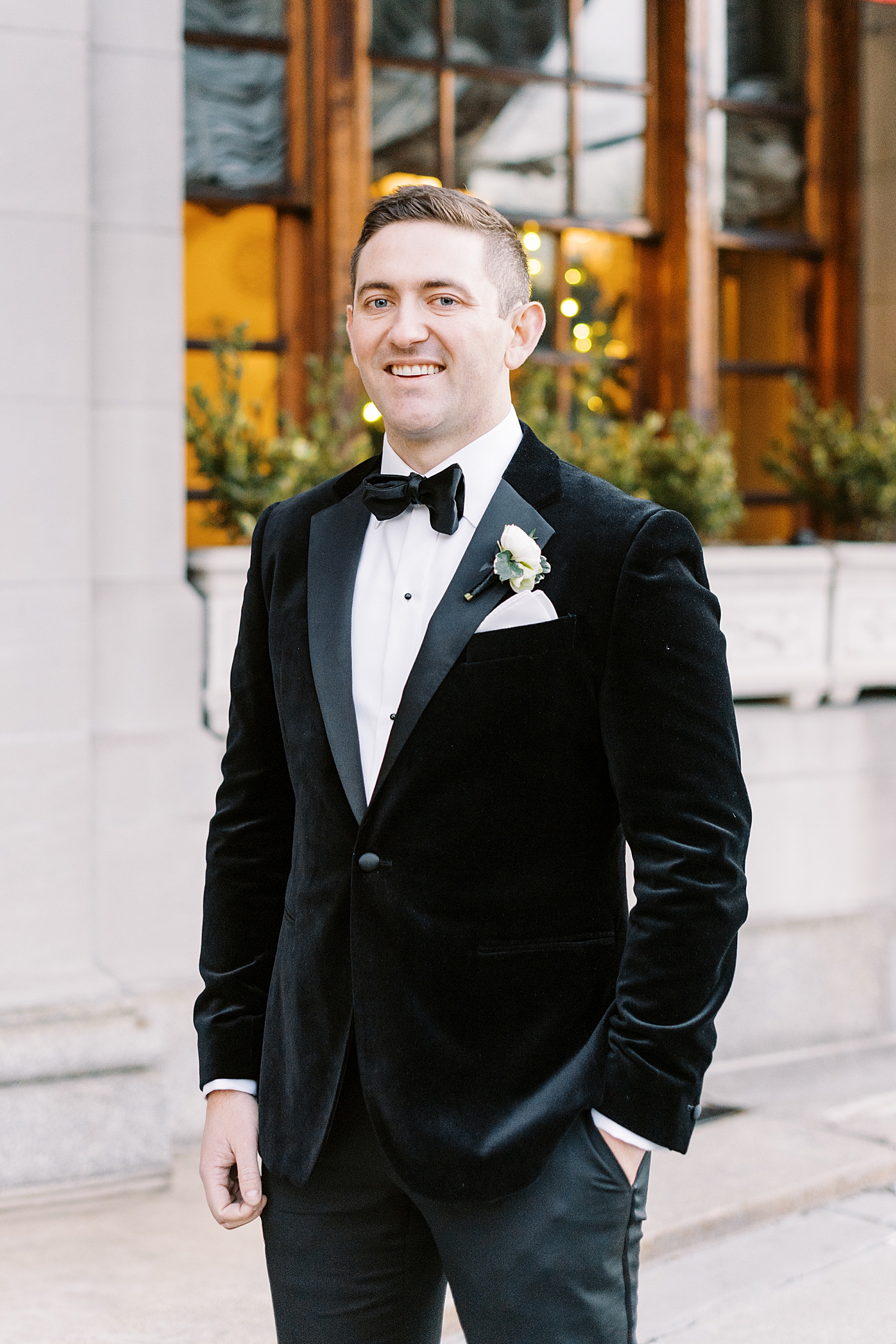 groom in velvet black tux on sidewalk by Lynne Reznick Photography
