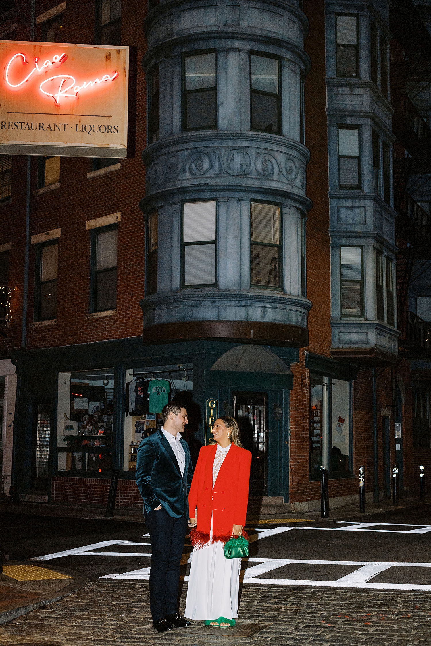 woman in bright red jacket stands with man on sidewalk for NYE wedding weekend