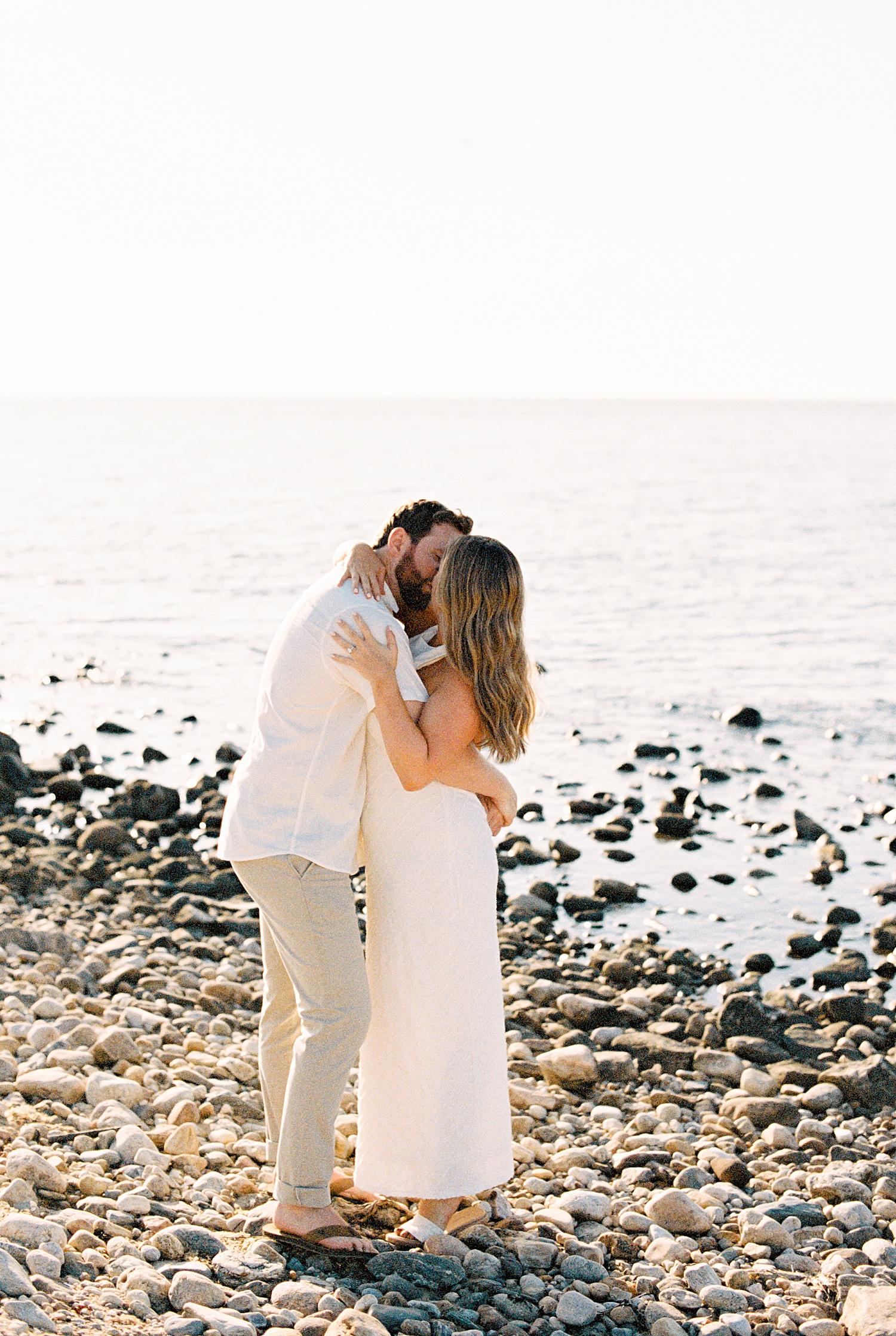 man kisses his bride-to-be on pebble beach for Montauk engagement session
