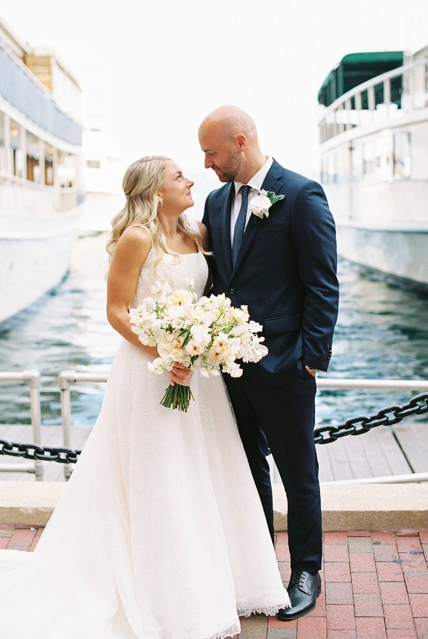 bride and groom stnad in front of waterfront at Boston Harbor Hotel 