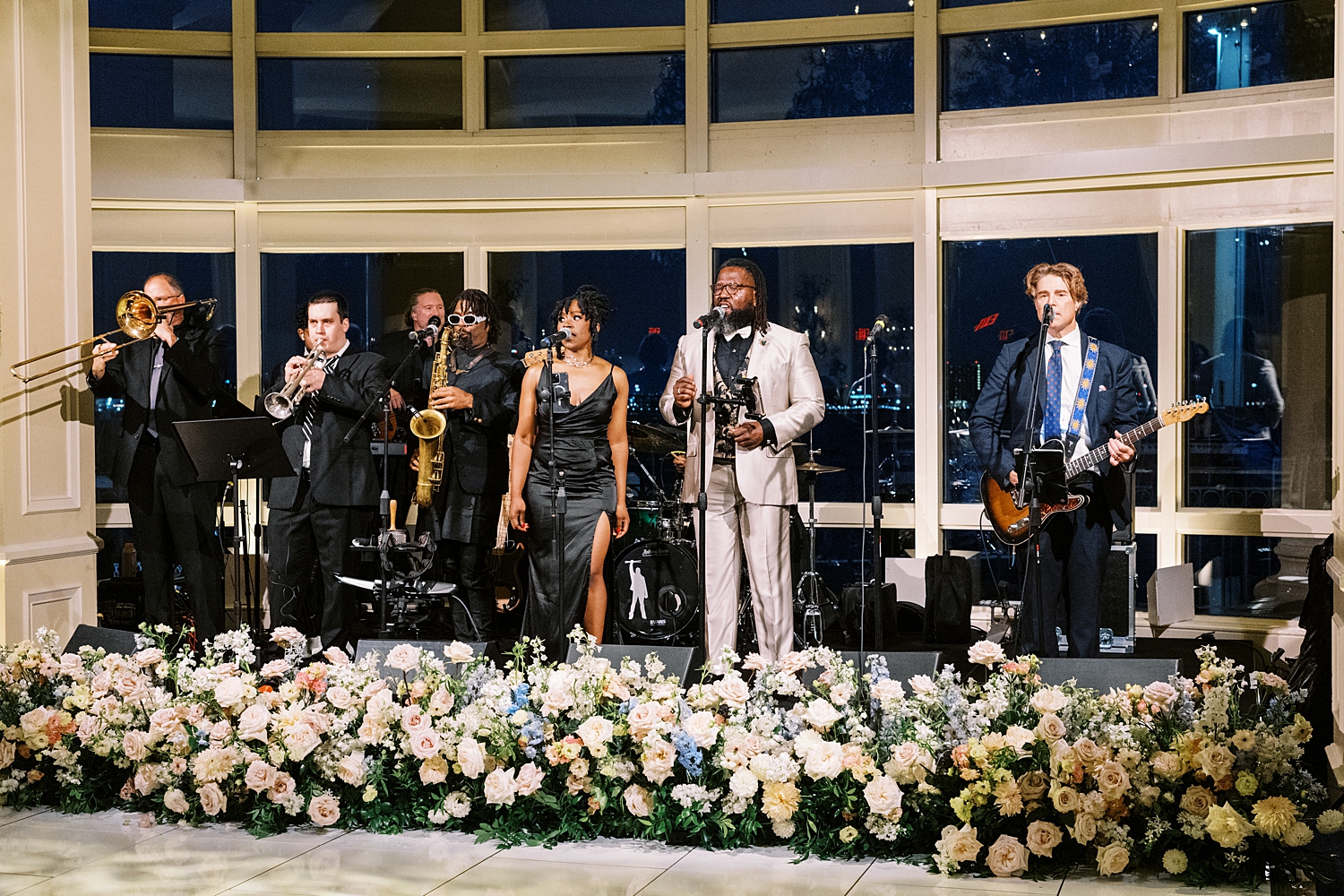band sings on reception stage surrounded by flowers by New England wedding photographer